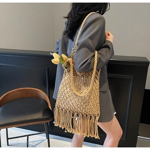 Detail showing the intricate hollow mesh weave and long fringe tassels of the woven tote bag