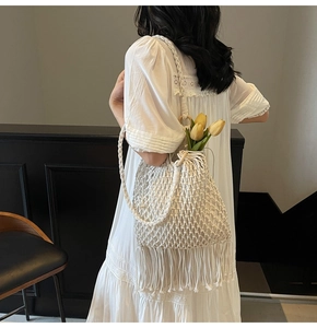 Close-up of beige macramé handwoven bucket bag featuring intricate tassels and cotton texture