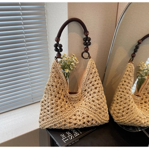 Detail of woven straw tote bag featuring contrast wooden bead handle for summer style