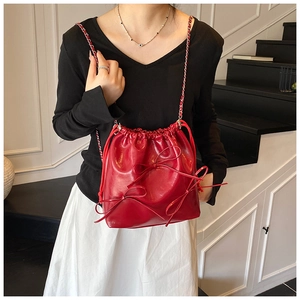 Detail of red bucket bag with bow decorations and red woven metal chain strap