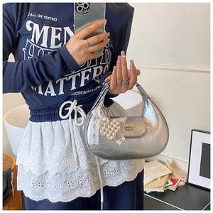 Detail of silver metallic crescent bag with pearl heart charm and white lace trim