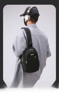 Close-up of the black nylon chest bag with MACHUGE logo and metallic zippers on the model