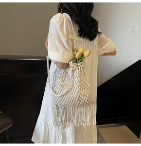 Close-up of white woven cotton shoulder bag with long tassels and wooden ring detail