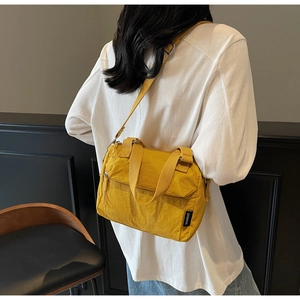 Close-up of mustard yellow nylon crossbody bag featuring a front zipper and adjustable strap