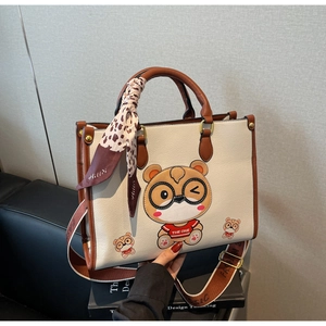 Detail of cute bear tote bag with litchi grain leather texture and silk scarf handle