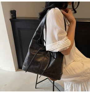 Détail d'un cabas vintage en cuir noir avec nœud coulissant et coutures renforcées