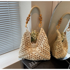Close-up of woven tote bag with wooden bead handle and decorative daisy flowers