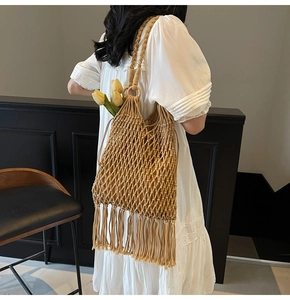 Detail of hand-woven hollow bucket bag with long tassels and yellow tulip accent