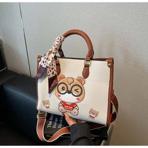Detail of white tote bag with bear print, leopard scarf handle, and wide strap