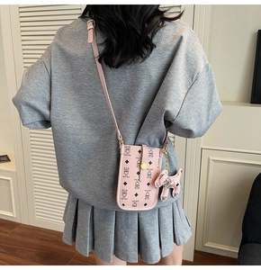 Pink cartoon bear crossbody bag with dog pendant shown on model for size perspective