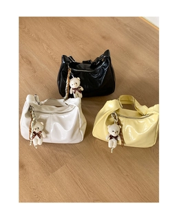Detailed view of glossy textured shoulder bags with braided rope and plush bear charms