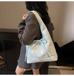 Détail latéral d'un grand sac hobo bleu clair avec un nœud décoratif élégant en cuir