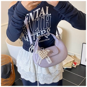 Detail of lilac crescent bag in crinkled patent leather with a pearl heart charm
