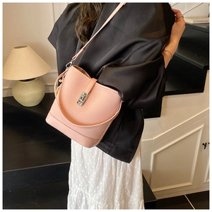 Detail of pink woven texture bucket bag with metallic twist lock and smooth leather trim