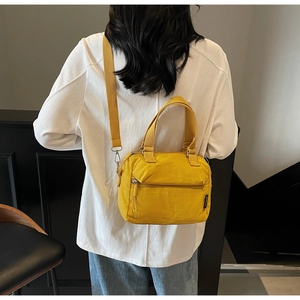 Détail d'un sac bandoulière en nylon jaune vif avec sangle réglable porté par un mannequin