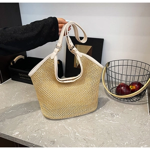 Détail d'un sac cabas en paille avec tissage à larges mailles et bandoulière en similicuir