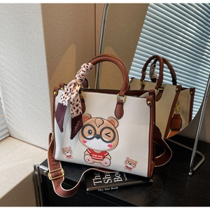 Close-up of cream tote bag featuring a cartoon bear print and stylish leopard scarf handle
