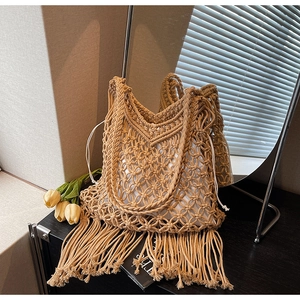 Detail of beige macrame tote bag with long fringe tassels and canvas drawstring liner