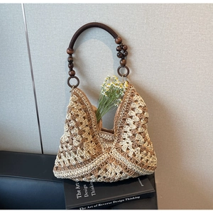 Detail of hand-crocheted woven tote bag featuring dark brown wooden bead handles