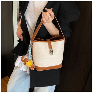 Detail of beige woven bucket bag with brown leather trim and cute elephant charm