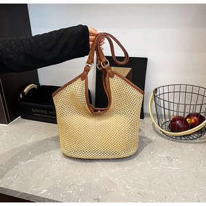 Détail d'un grand sac cabas en paille avec tissage beige et poignées en cuir marron