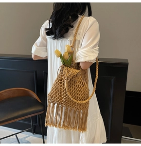 Detail of hand-woven ginger bucket bag with long fringe and elegant woven shoulder strap