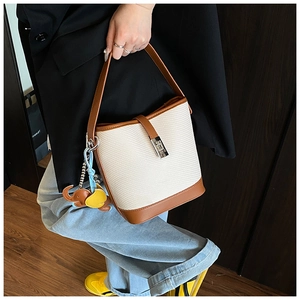 Detail of woven bucket bag with leather trim and cute elephant charms in a lifestyle setting