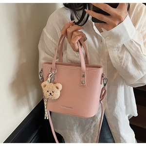Pink lychee texture bucket bag with cute bear charm and striped scarf detail in use