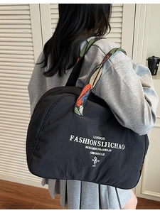 Black large nylon tote bag with colorful jacquard strap worn by model on shoulder