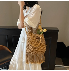 Detail view of beige macrame woven bucket bag featuring long tassels and wooden handle