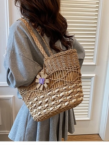 Large woven straw tote bag with white stripes and purple flower pendant for beach vacations