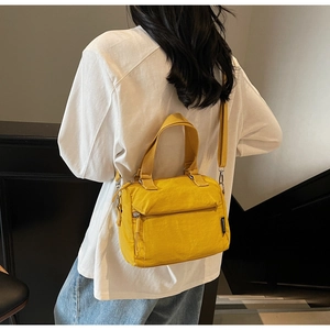 Modèle portant un sac seau en nylon jaune avec bandoulière amovible et poignée