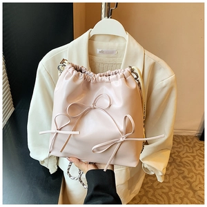 Detail of light pink PU leather bucket bag with handmade bows and silver chain strap