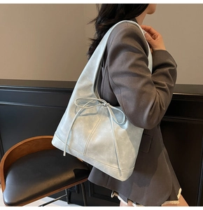 Détail du sac Hobo bleu clair avec des nœuds décoratifs sur le côté et une texture en cuir synthétique