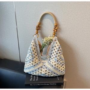 Detail of woven tote bag featuring blue crochet patterns and wooden bead handles