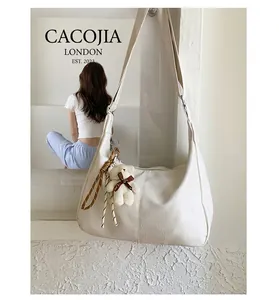 Close-up of white crocodile pattern hobo bag with cute plush bear charm and woven strap