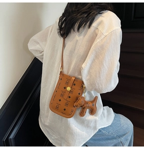 Detail of a brown cartoon teddy bear pattern crossbody bag with a cute dog charm