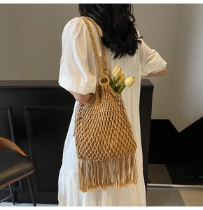 Detail of hand-woven hollow mesh tote bag with long tassels and interior flower styling