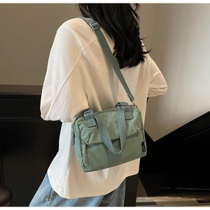 Detail of mint green nylon bag showing the adjustable shoulder strap and texture on model