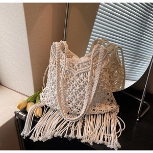 Detail of bohemian white macrame tote bag featuring long tassels and interior drawstring bag