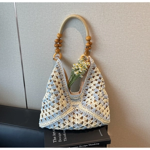 Detail of handwoven crochet tote bag with wooden bead handles and floral accent