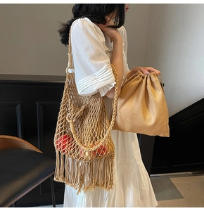 Detail showing the woven texture and long tassels of the hollowed-out beige bucket bag