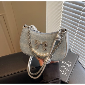 Detail of light blue underarm bag featuring silver bow buckle and faux pearl chain