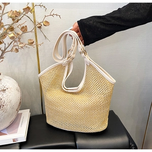 Vue détaillée du sac cabas en paille tissée avec anses en cuir blanc et boucles dorées