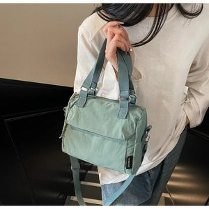 Detail of mint green nylon handbag with double handles and zipper pocket for casual daily use