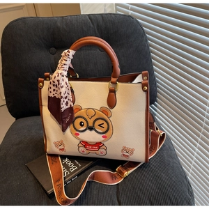Detail of white tote bag with bear print, brown strap and decorative silk scarf on chair