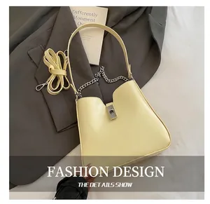 Detail der cremefarbenen Beuteltasche mit silbernem Drehverschluss und Dekokette auf Sakko