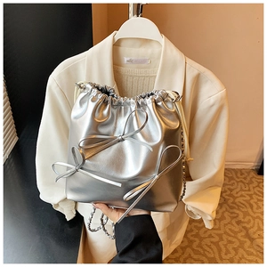 Detail of silver metallic bucket bag with ribbon accents and chain strap