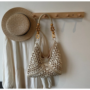 Close-up of woven straw tote bag featuring decorative brown wood beads and wavy textures
