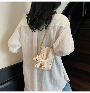 Detail of beige crossbody phone bag with teddy bear print and 3D bear charm